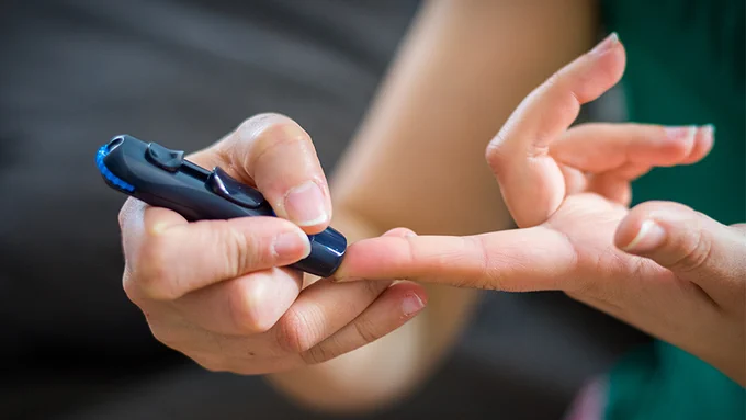 A person pricking the end of their finger for blood for a glucose test. 