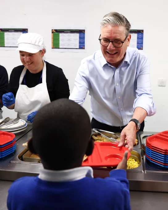 A photo of Prime Minister Keir Starmer serving a child their school meal.