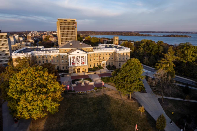 Aerial view of Bascom Hall at sunrise, with campus buildings, Picnic Point, and Lake Mendota in the background.