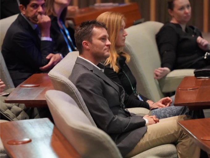 Attendees sitting and listening attentively at a conference in a formal setting.