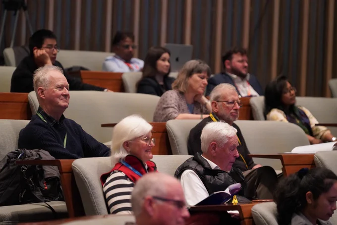 Audience members sitting and listening attentively in a conference hall.