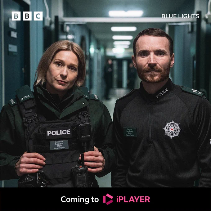 Grace Ellis (Sian Brooke) and Stevie Neill (Martin McCann) stand in a corridor in black police uniform