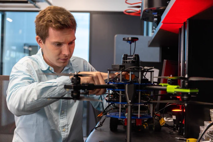A man works on a drone in an engineering lab. 