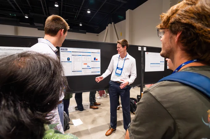 Presenter discussing posters with a group of attendees at a conference.