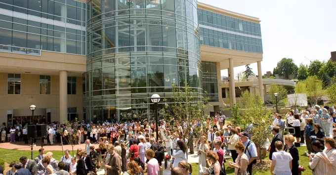 A large group of people gathered outside the University of Michigan CVC, a modern glass building, during its opening event in late 2003.
