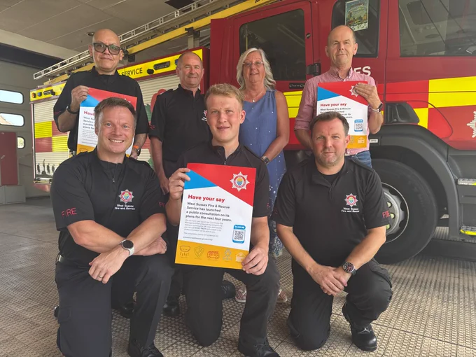 Members of staff holding posters in front of a fire engine