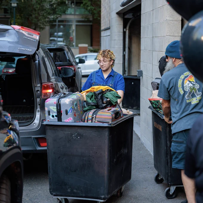 Person rolling suitcases in a black rolling cart.