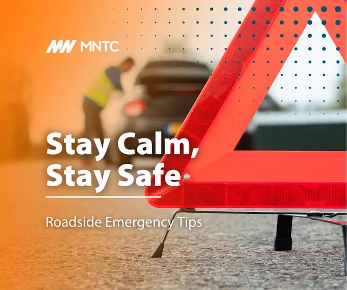 An image featuring a roadside emergency scene with a reflective orange triangle in the foreground and a person working on a disabled vehicle in the background. The text "Stay Calm, Stay Safe. Roadside Emergency Tips" is displayed, and the MNTC logo appears in the upper left corner.