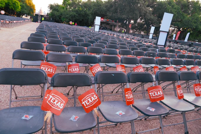 Rows of empty chairs with burnt orange University of Texas "Gone to Texas" fans arranged for an outdoor event.