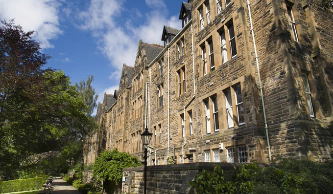 Cross-step gable Victorian tenement building, with a tree-lined avenue in front.