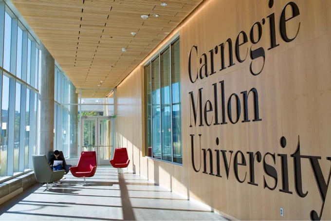 the inside hallway in the Tepper building features a large Carnegie Mellon University logo etched into the wood on the right side of the hallway