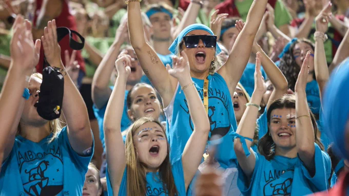 Students in light blue shirts cheering enthusiastically at the pep rally.