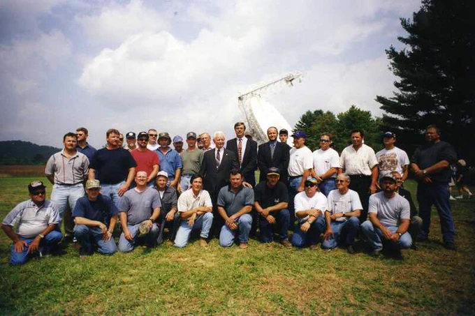 Photo of a group of people posing in front of the Green Bank Telescope at its dedication, circa 2000.