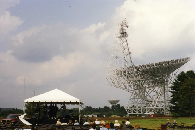 Photo from the Green Bank Telescope's dedication in 2000, featuring a large white tent and crowd of people in front of the large radio telescope.