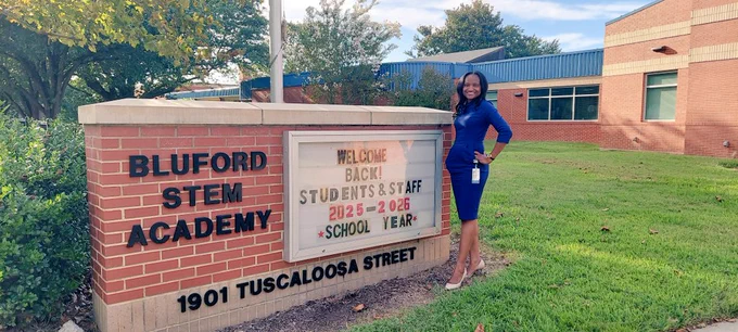 Photo of a person standing in front of a school marquee. 