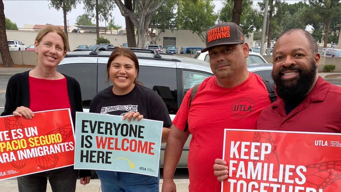 Members pose holding signs welcoming immigrant families.