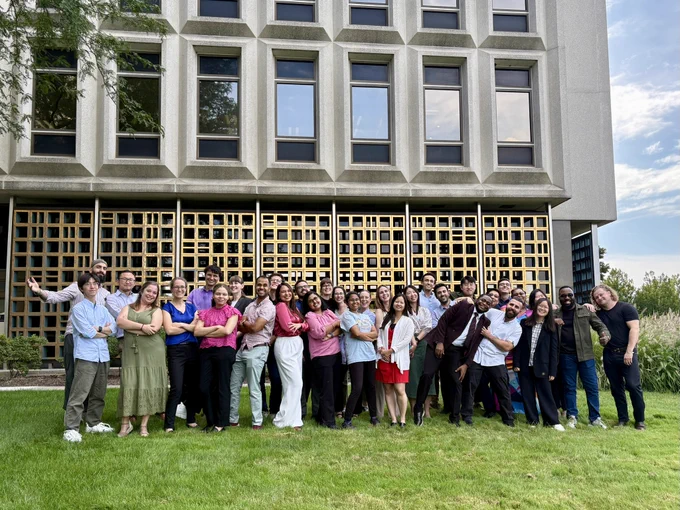 A group of early-career scientists gathered on a green lawn in front of the CAS headquarters