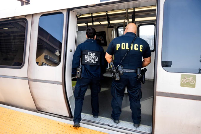 A crisis intervention specialist and police officer board a BART train