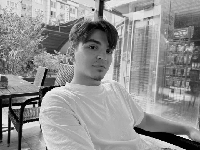 photo of Salih, a young student, sitting outside a café looking at the camera