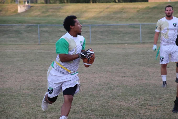 A player runs forward with the footbasll, looking for an open teammate to throw the ball to.