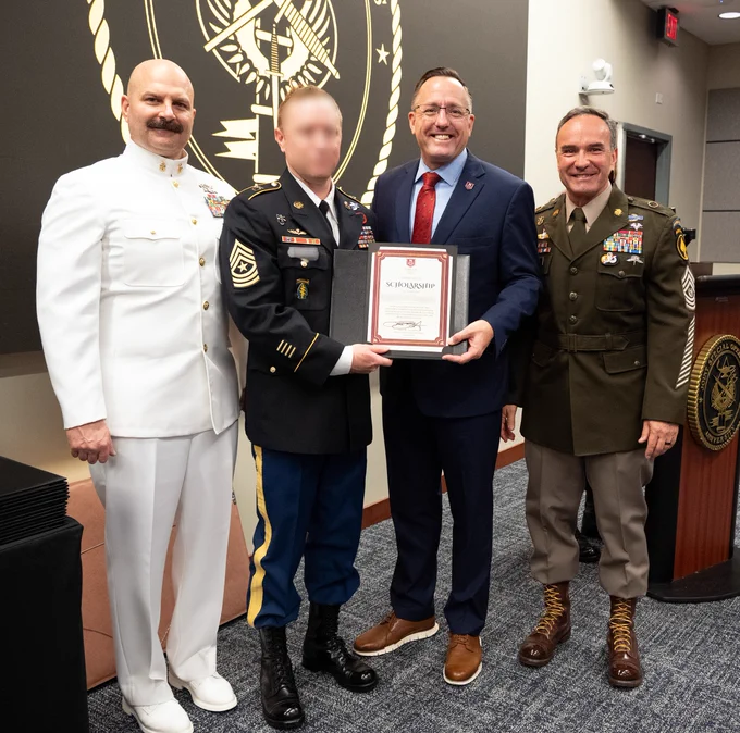 Men in uniform present a soldier with an award.