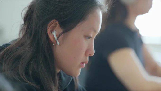 Student who appears to be studying at a desk while wearing earphones