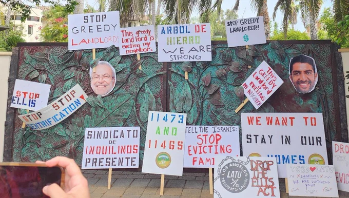 Photo of the Israni family mansion's gate decorated with their faces and a variety of protest signs asking them to stop evicting families under the Ellis Act.
