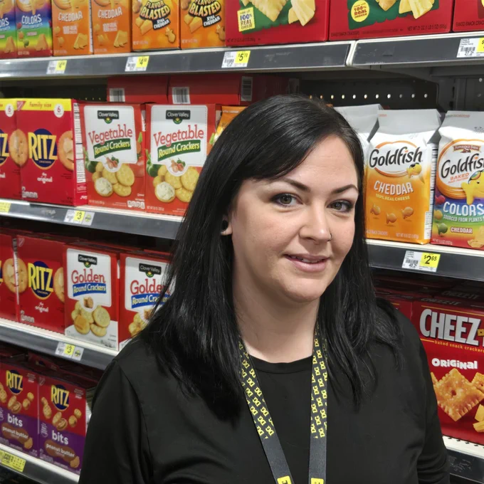 Store manager Katie smiling in store aisle. 