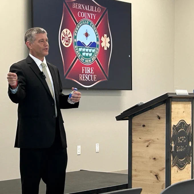 Jonathan Cohen giving a presentation in front of a screen displaying the Bernalillo County Fire Rescue logo.