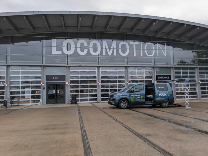 A photo of the exterior of the Locomotion building with an accessible taxi outside.