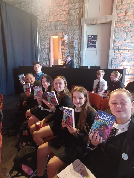 A row of pupils holding up Nathaneal Lessore's book "What Happens Online."