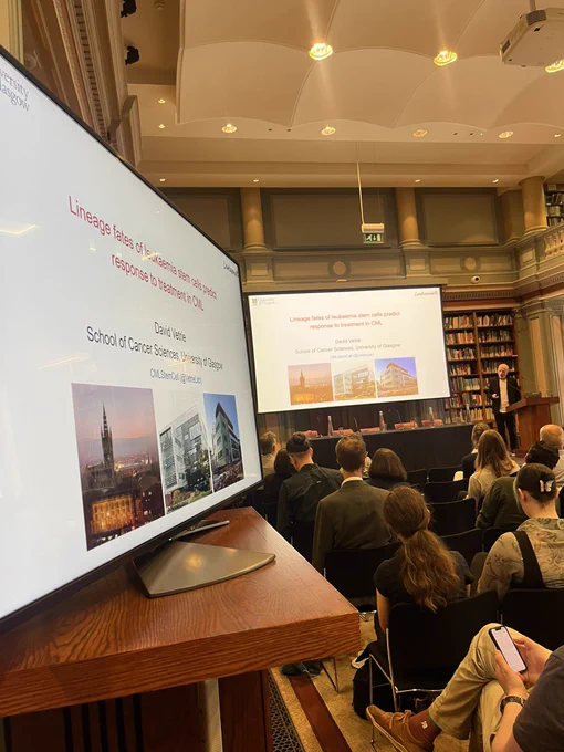 Professor David Vetrie delivers a talk on his research into CML. The text on the screen reads, ‘Lineage fates of leukaemia stem cells predict response to treatment in CML’