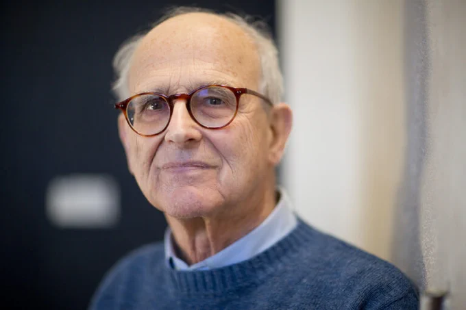 Rai wearing round glasses and a warm sweater. Photographed in 2016 by Bryce Vickmark