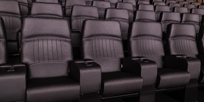 Rows of empty black seats in a movie theatre.