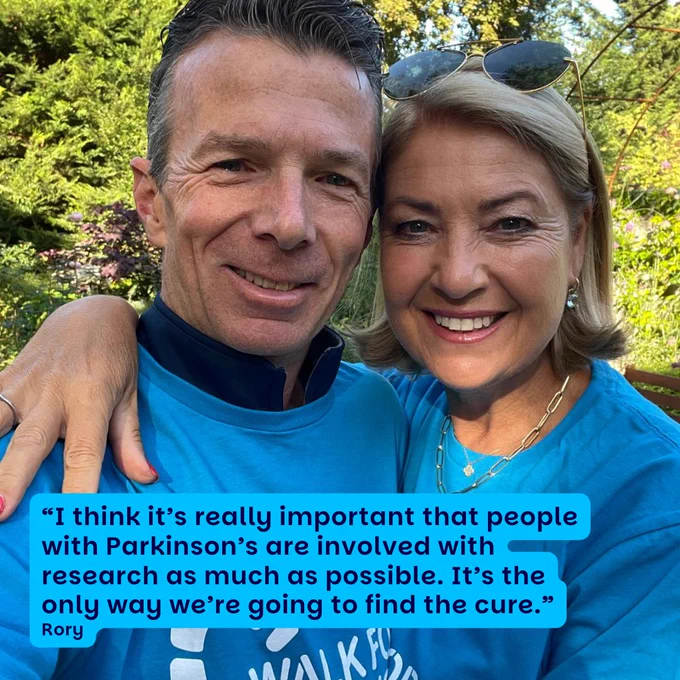Rory and Janine are standing hugging each other and smiling, they are both wearing light blue Parkinson's UK t-shirts. There is navy writing in the bottom corner which reads: “I think it’s really important that people with Parkinson’s are involved with research as much as possible. It’s the only way we’re going to find the cure.” - Rory