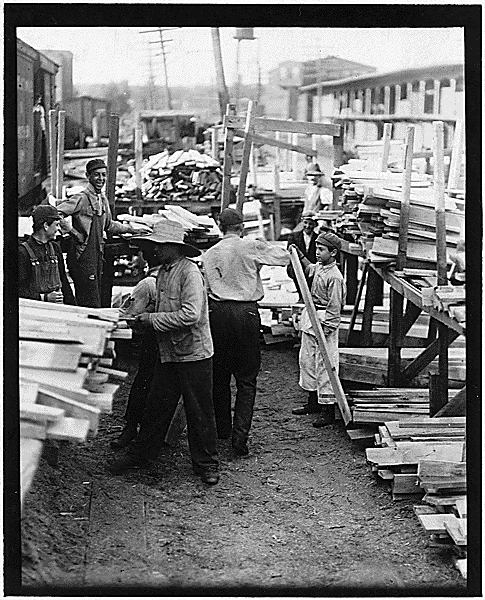 Boys of various ages work in a lumber yard.