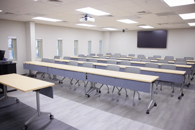 Interior space in the McLure Library. Featuring long desks, chairs and a television hanging on the back wall.