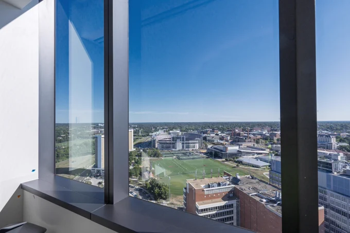 View from a high-rise office window overlooking a university campus with clear blue skies.