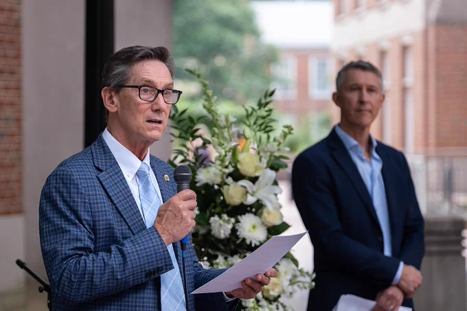 College dean Jim White speaks into a microphone at the Zijie Yan memorial site