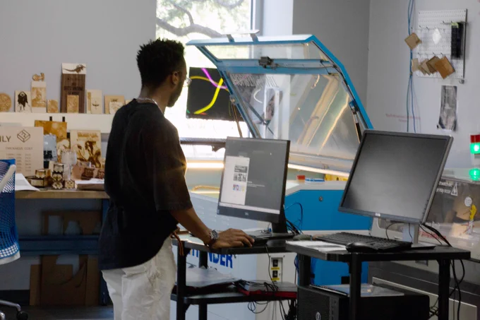 [ID: Pictured is a photo of a student working on a machine in the FabLab on the first floor of the UTA Central Library.]