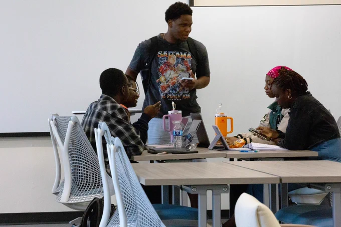 [ID: Pictured is a photo of five students studying at a table in the Day Family Research Lab on the fifth floor of the UTA Central Library.]