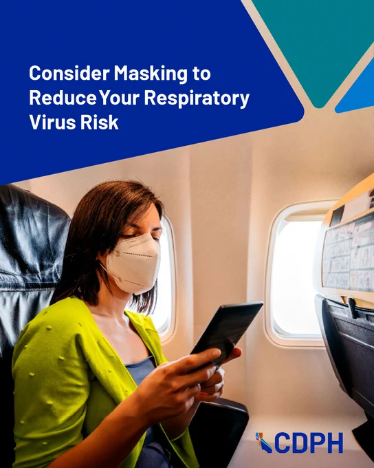Person wearing a mask sitting by an airplane window, using a smartphone, under a notice from CDPH recommending masks to reduce respiratory virus risk.