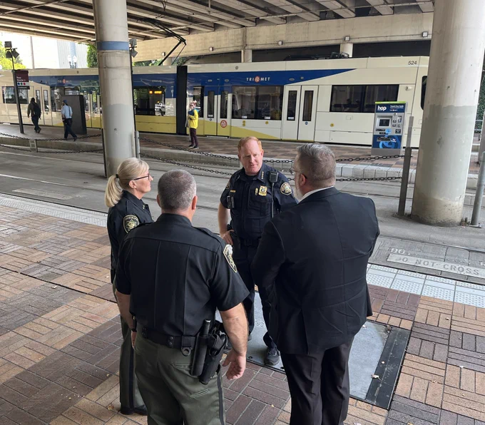 Chief Day speaks with the Sheriff and others at a MAX stop.
