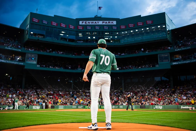 Payton Tolle stands on the mound at Fenway Park, his back to the camera, with the facade in background. 