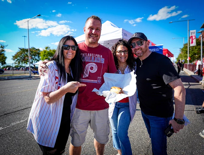Fans smile with cheesesteak from Jesús Luzardo's Cheesesteak for Charity event.