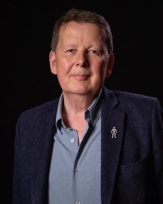 Image of the late, great Bill Turnbull, smiling and dressed in a dark blazer with a casual shirt, against a black background.