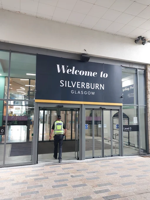 Police officer walking through a door at Silverburn that's displaying 'Welcome to Silverburn'