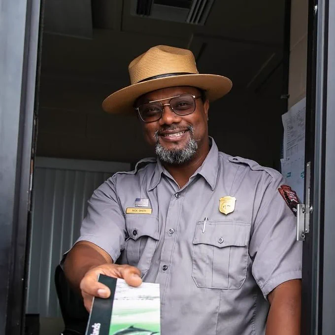 A ranger handing out a park unigrid from entrance station. 