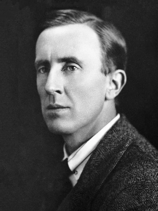 Fotografía en blanco y negro de J.R.R. Tolkien. Es joven, viste camisa, corbata y gabardina. Tiene el pelo bien peinado y su rostro está afeitado, con un semblante serio. Está un poco de lado.