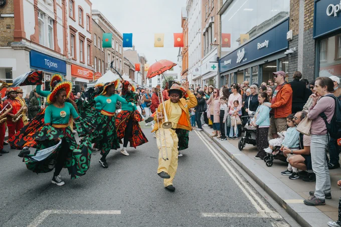 Performers and musicians parading down George Street as many people watch on